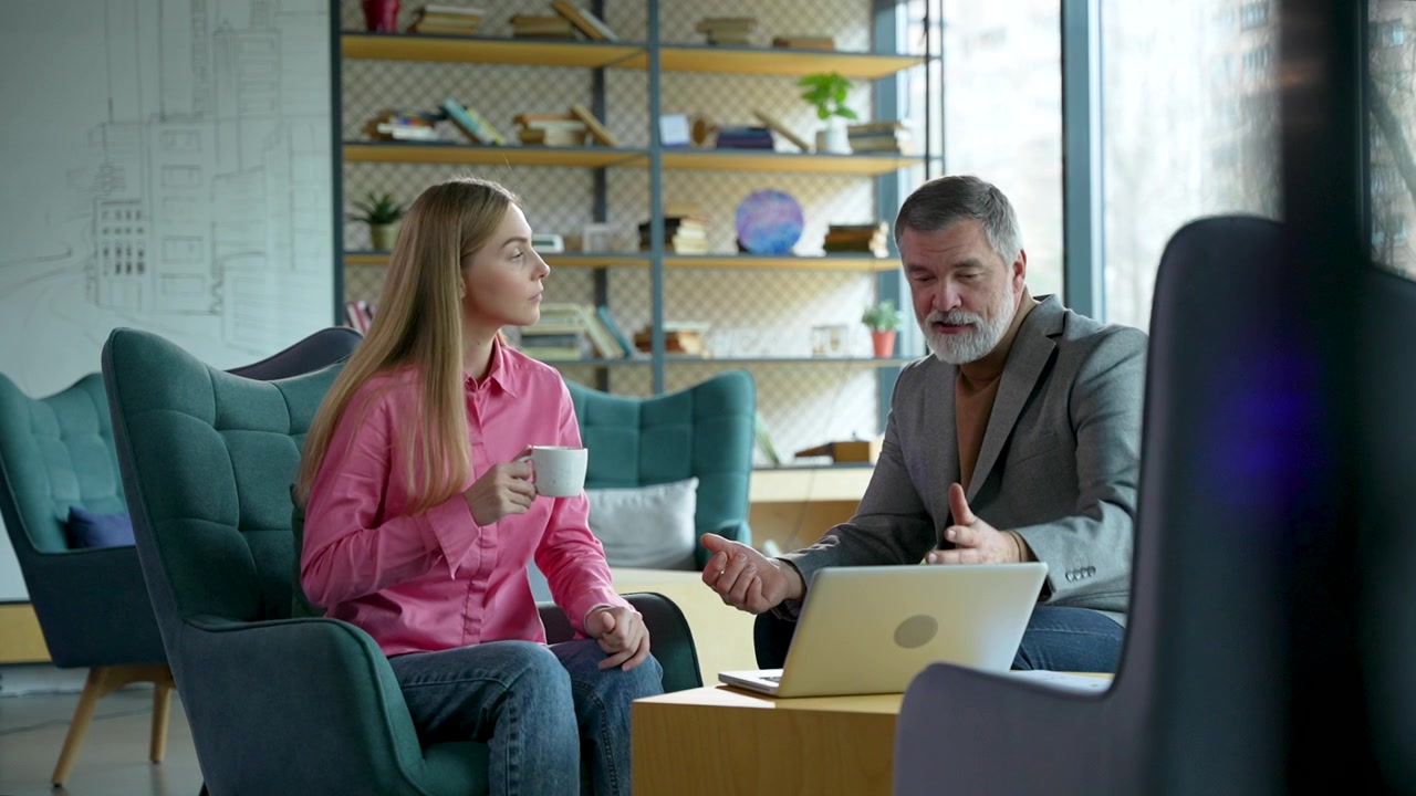 Professional Business Meeting Between Young Woman and Mature Man in Modern Office
