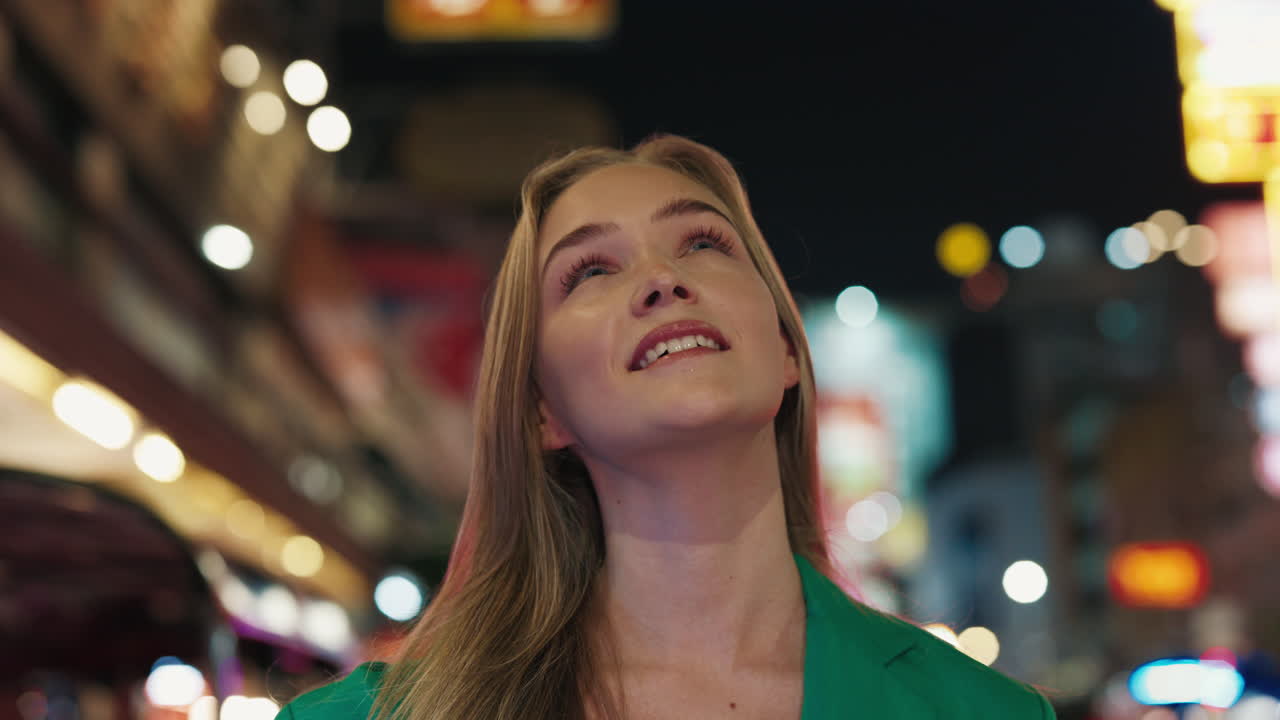 Young woman looking up at night city lights