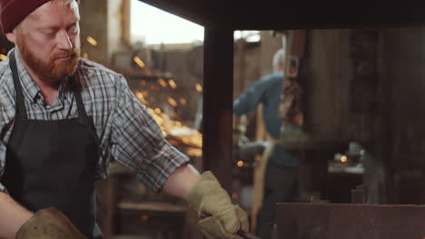 herrero cuidando el fuego de forja en el taller