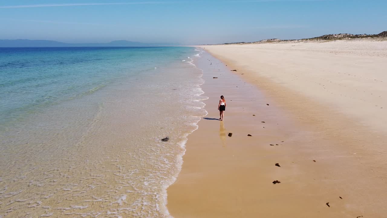 playa comporta en la costa oeste de portugal - vista aérea de drones de una chica turista sola caminando en la playa de arena