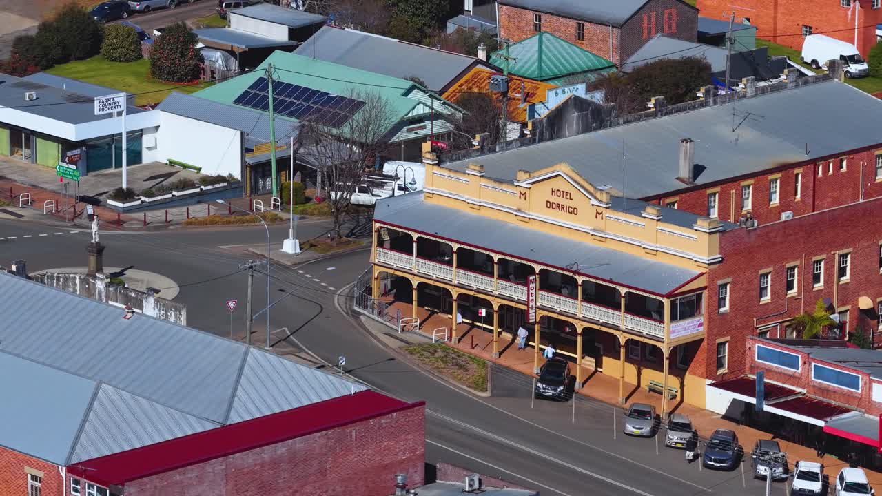 Drone ascends over rural Dorrigo town, revealing historic buildings, shops, cars, and bright daylight