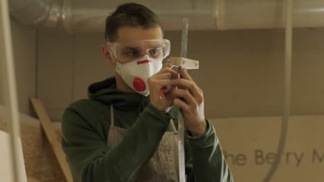 hardworking professional carpenter in mask and glasses holding a ruler and pencil