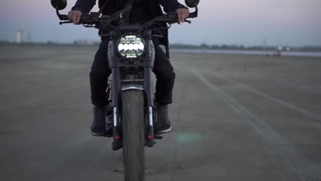 close up of biker's ride on black sport bike with switched front headlight, unrecognizable