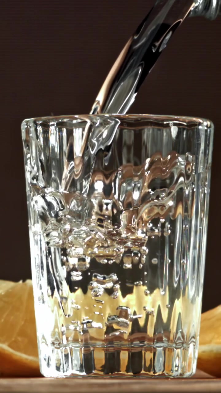 Rót chất lỏng trong suốt vào ly shot ở chế độ chuyển động chậm
