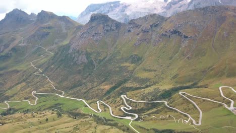 a long winding mountain road in the dolomites of northern italy, aerial drone tilt-down reveal shot