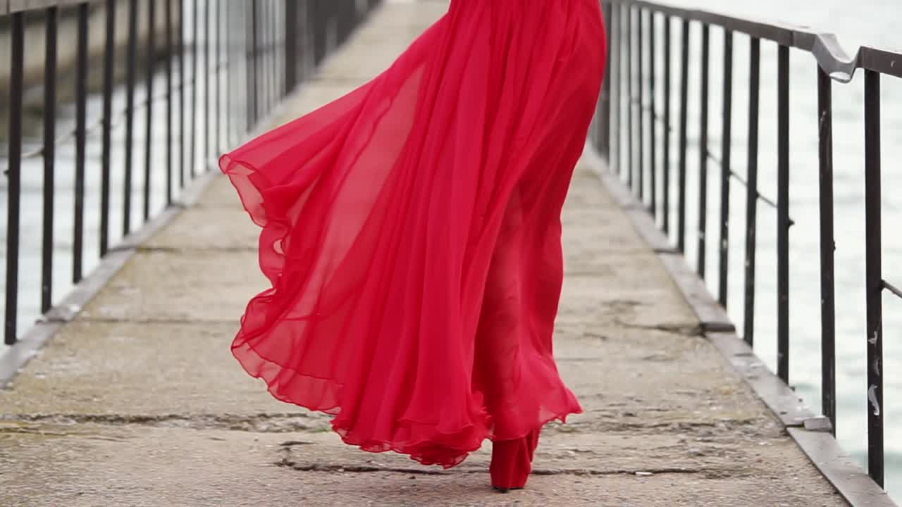 Woman in a Red Dress Walking on a Pier