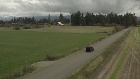 Drone-actively-following-a-red-Jeep-Wrangler-on-a-country-road-in-4k