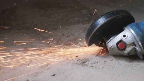 circular metal saw cutting a metal part in concrete floor generation orange sparks. worker cuts metal with orange sparks flying. slow motion