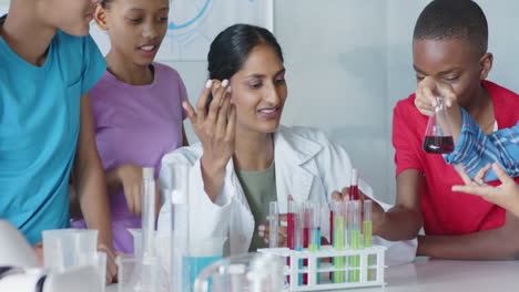 conducting science experiment with test tubes, students in school supervised by teacher