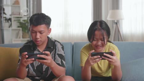 siblings playing games on smartphones at home