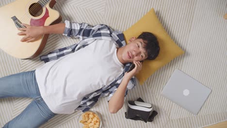 teenager relaxing at home with phone, vr headset, and guitar