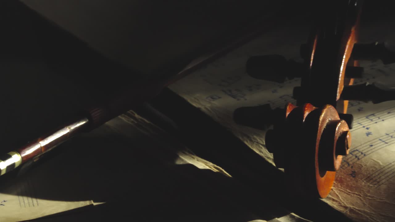 Aged Violin scroll shape revealed in dramatic moody shadows close-up