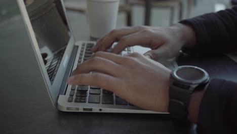 fotografía recortada de un hombre escribiendo en una computadora portátil