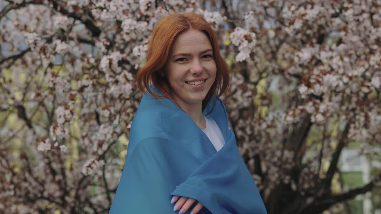 Woman in Blue Cloth in Front of Cherry Blossoms
