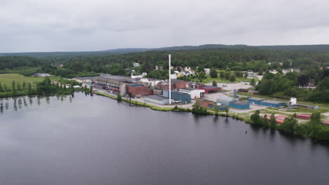 establishing drone shot of hafrestroms foretagspark during the day with body of water and trees, industry in asensbruk, dalsland, sweden