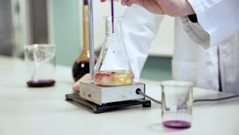 toma en cámara lenta de un científico mezclando diferentes sustancias en un vaso, usando una chaqueta blanca en un laboratorio