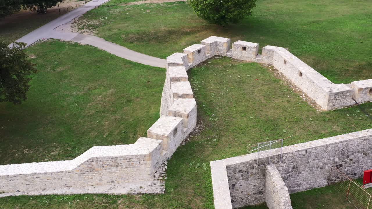 White stone wall of Pocitelj castle and green grass on rooftop, Bosnia and Herzegovina, aerial