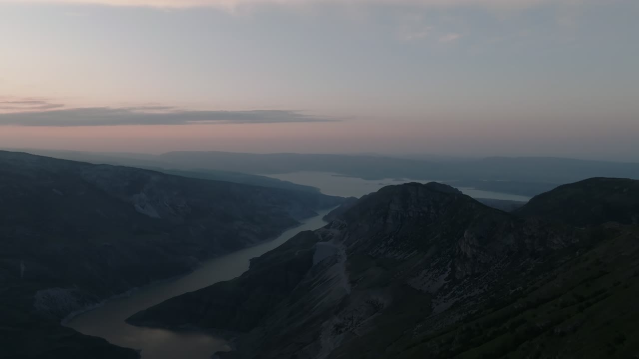 Aerial footage of the Main Sulak Canyon with a winding river between steep mountain ridges at sunrise, Dagestan, Russia, serene landscape in soft morning light