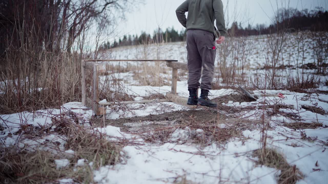 Mand bygger gør-det-selv vildmarksbad af træ udendørs om vinteren.
