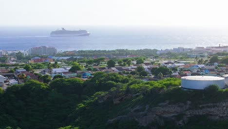 órbita-Aérea-Alrededor-De-La-Ciudad-Costera-Local-Con-Un-Gran-Crucero-Entrando-Al-Puerto,-Seri-Domi-Curacao