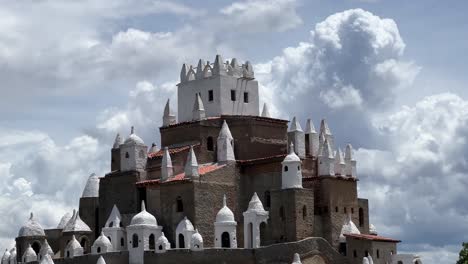 tilting up medium shot of the large incredible castle "zé dos montes" built by jose by hand with bricks from instructions by god in rio grande do norte, brazil on a warm sunny cloudy day