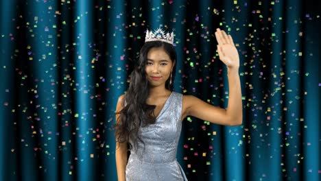 Miss-beauty-pageant-Asian-woman-winner-stands-in-front-of-the-stage-curtains-and-waves-as-confetti-falls-in-celebration-of-her-win