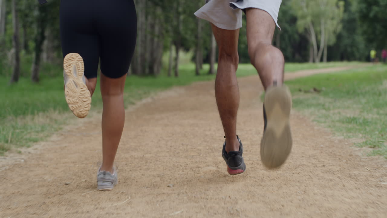 primer plano de piernas de pareja en forma corriendo en un bosque