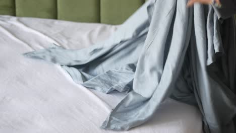 person making bed with blue sheets