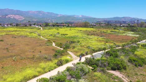 Antenne-Eines-Mannes,-Der-Sein-Fahrrad-Mit-Den-Bergen-Von-Santa-Barbara-Im-Hintergrund-In-Der-Nähe-Von-Carpinteria-California-1-Fährt