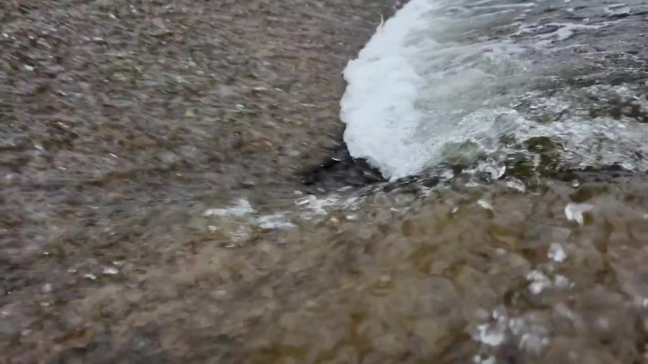 Cascata d'acqua del fiume al rallentatore su barriera di cemento.