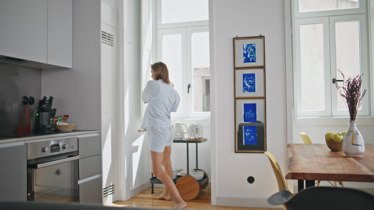 Happy woman fooling around in apartment kitchen. Cheerful girl having fun home