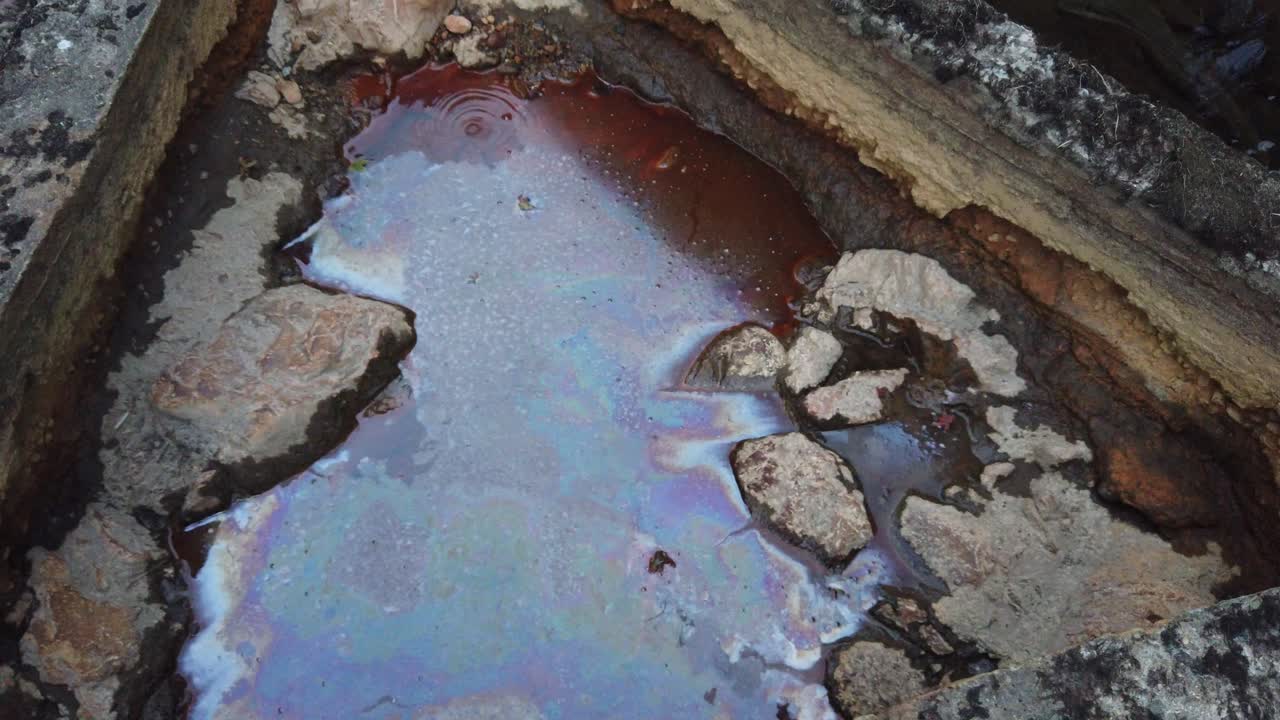 Agua ferruginosa en un río Onsen natural en Tamba, Japón, con colores de bronce y arcoíris debido a los minerales.