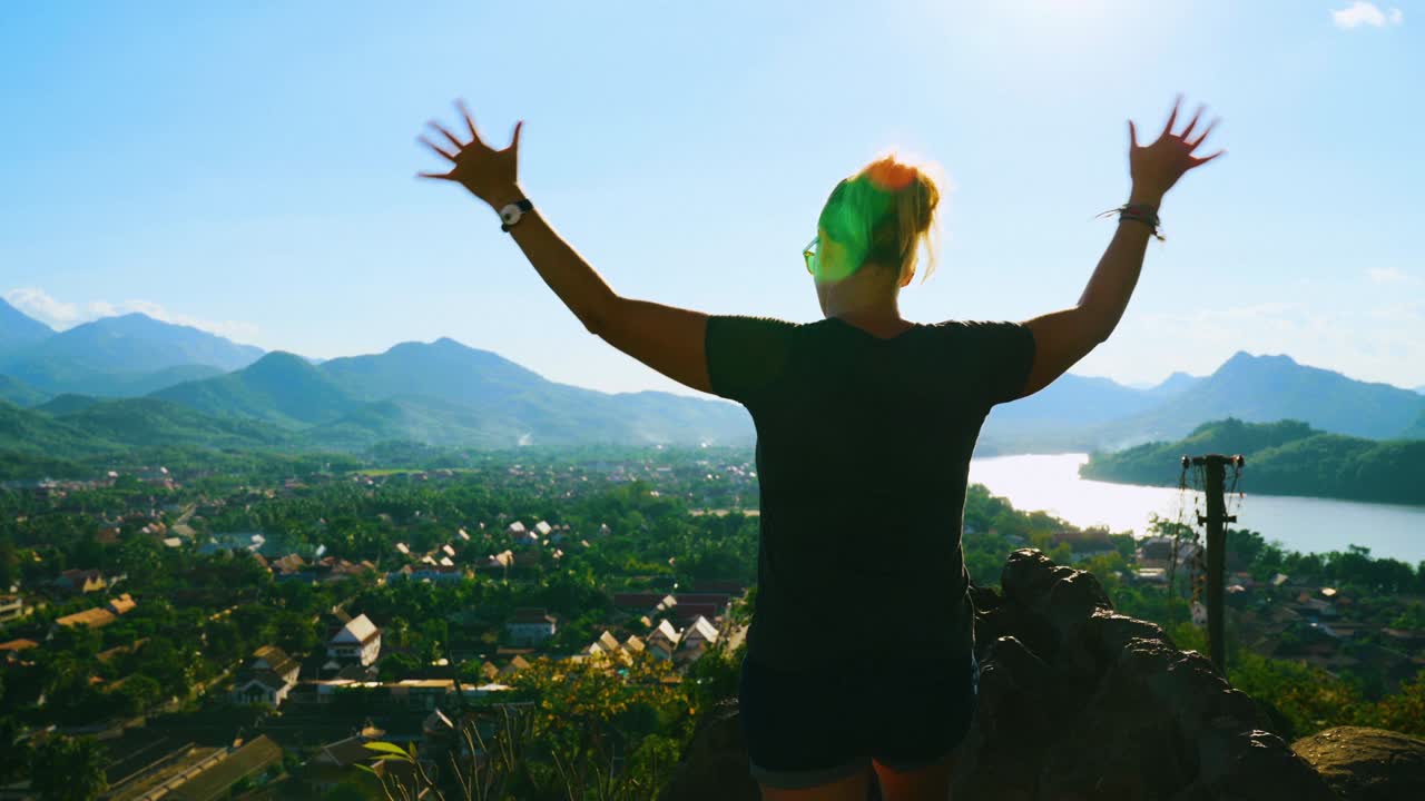 여행을 즐기는 여성 여행자의 뒷면, 자유로운 느낌에 대한 지출, 성취와 함께 팔을 들어 올리는 모습.
