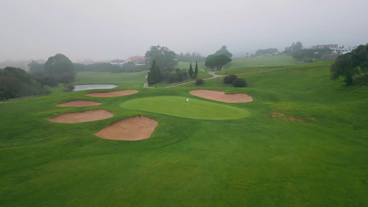 Fog descending lush nature greenery at golf course aerial view. Morning mist
