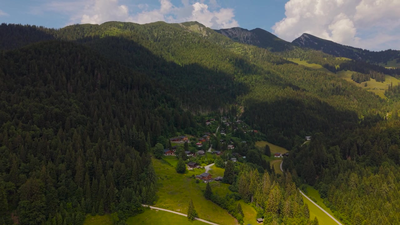 Bujnie zielona dolina Heutal w Alpach Salzburskich, otoczona gęstymi lasami sosnowymi i tradycyjnymi alpejskimi chatami