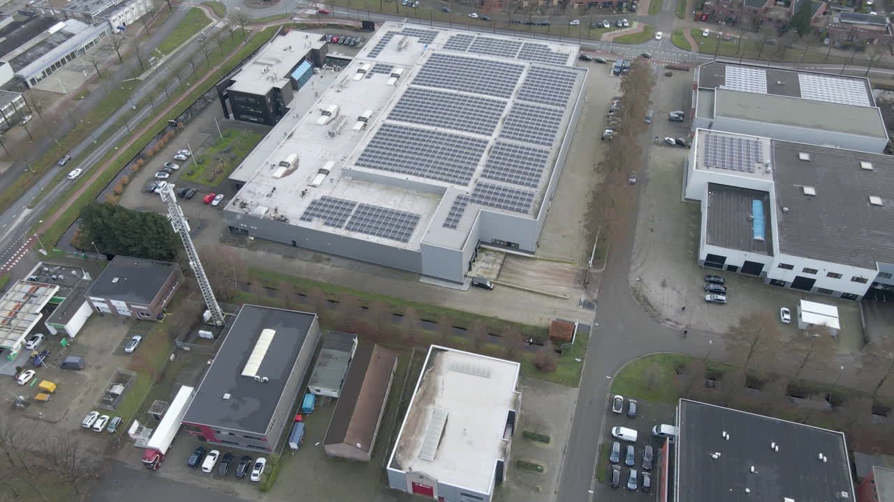 Luftfoto, der vipper ned mod et industrielt tag fyldt med solpaneler.