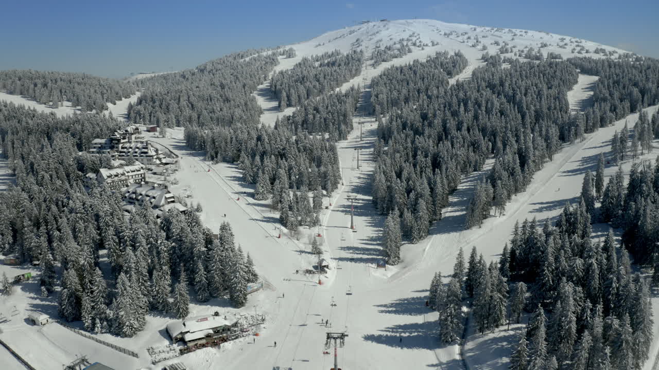 Panoramic Aerial View of a Snow-Covered Ski Resort with Slopes and Chairlifts on a Sunny Winter Day