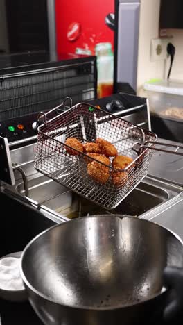 nuggets de pollo fritos que se preparan en una freidora comercial