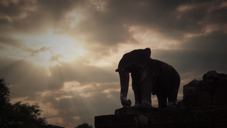 Estatua-De-Elefante-De-Silueta-En-El-Parque-De-Angkor-Con-Impresionantes-Rayos-De-Sol-Moviéndose-Con-Las-Nubes-De-Fondo