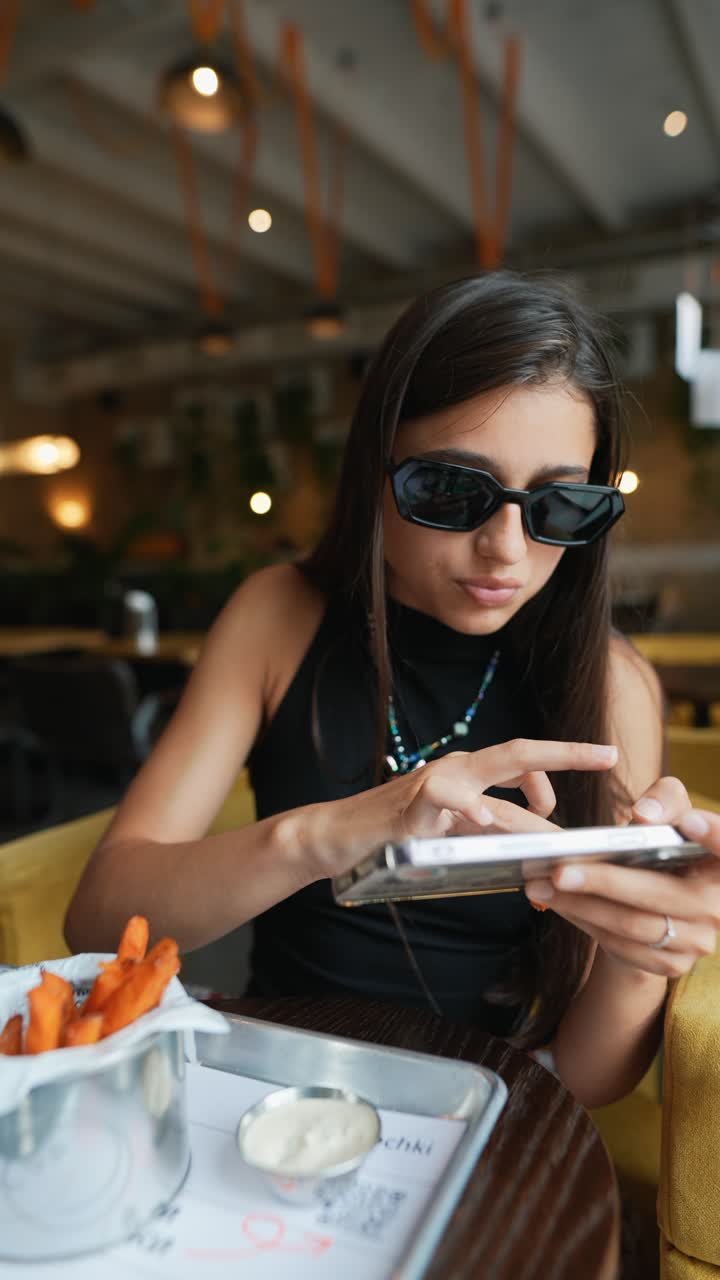 mujer usando el teléfono mientras come papas fritas en un café