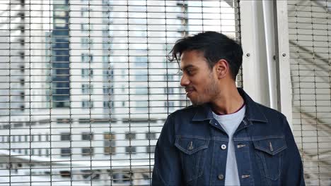 Fashionable-guy-in-jean-jacket-looks-behind-him-out-into-Denver-Union-Station-and-looks-back-dreamily