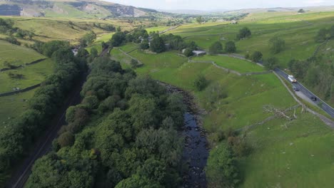 drone footage flying over a beautiful shallow tree and grass lined river valley in sunny rural yorkshire, uk