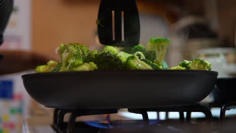 revolviendo el brócoli en la estufa para una comida casera - ángulo bajo en cámara lenta