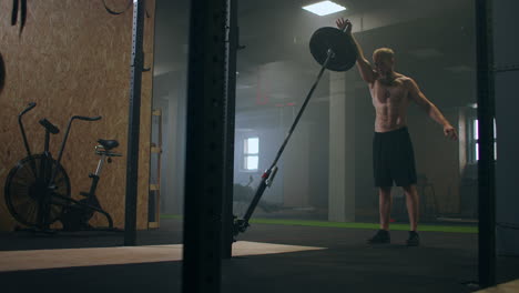 A-man-working-out-in-the-gym-pushes-a-landmine-bar-with-his-hand