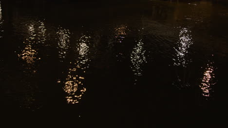 the water glistens and shimmers from the light of the surrounding bridges as the current flows past in a close up shot