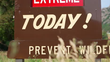 extreme fire danger today prevent wildfire red and white sign on brown metal board wide shot panning down and to the right at national park mountains ogden utah canyon