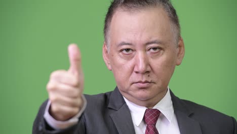 성숙한 일본인 사업가들이 엄지손가락을 올리고 있습니다.