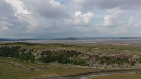 Aerial-lowering-shot-showing-a-hill-located-in-a-coastal-bay,-on-a-bright-sunny-day