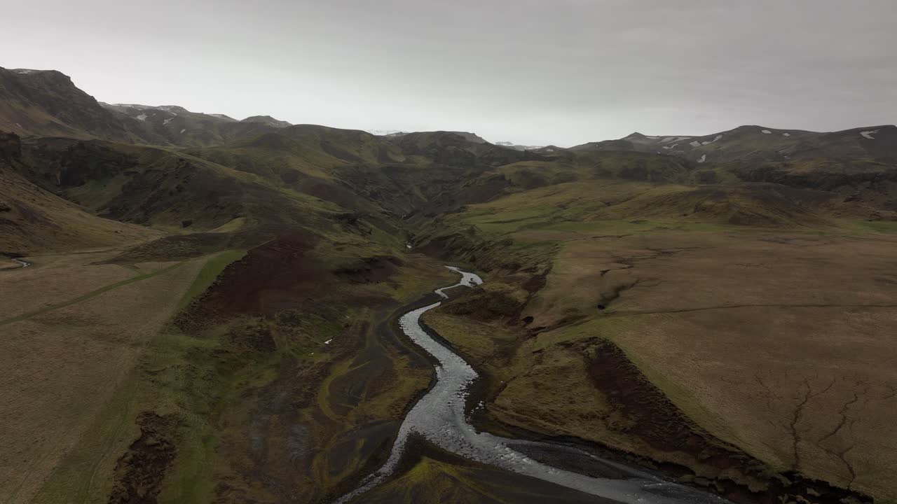 fotografía aérea de un río que se curva a través del vasto y estéril valle de brókarjökull, islandia, rodeado de escarpadas montañas y terreno abierto