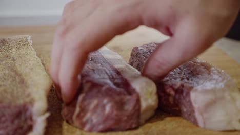 Cierre-Las-Manos-Del-Chef-Volteando-Filetes-De-Carne-Sazonados-Con-Pimienta,-Ajo-En-Polvo-Y-Romero-En-Polvo